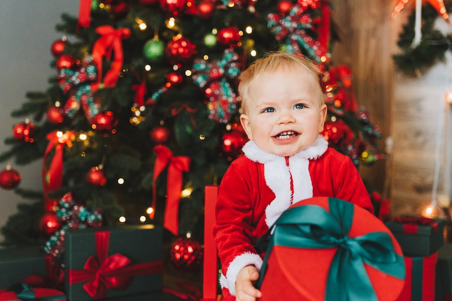 a baby boy holding a red christmas present