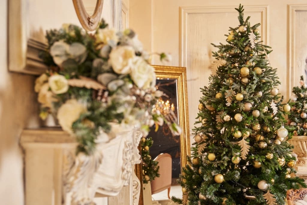 a room decorated with Christmas tree, flowers and in gold