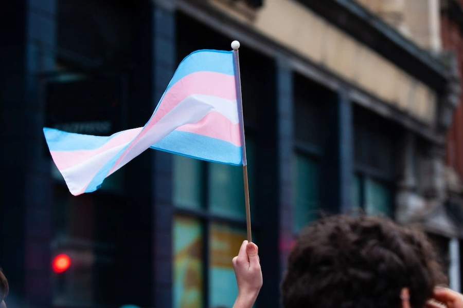 a man holding a small trans pride flag